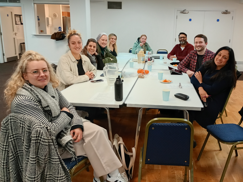 A group of people around a table talking and writing.