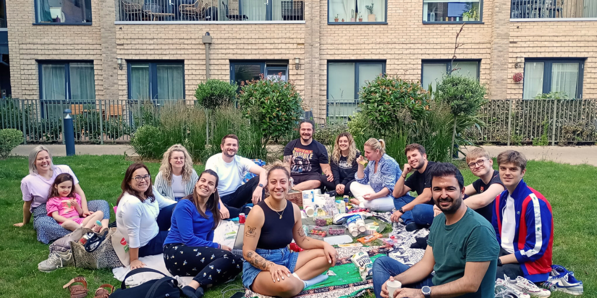 Residents picnic together on a green space by their homes. 