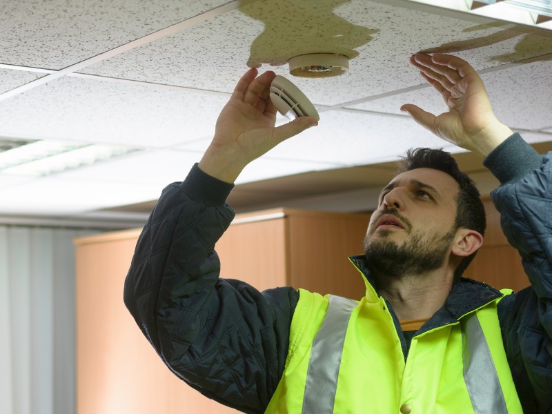A man tests a fire alarm works. 